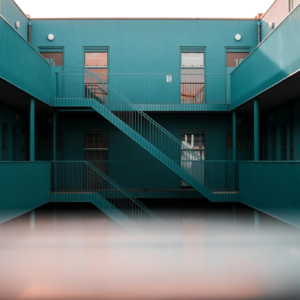 Modern interior view of a blue apartment complex featuring staircases and doors.